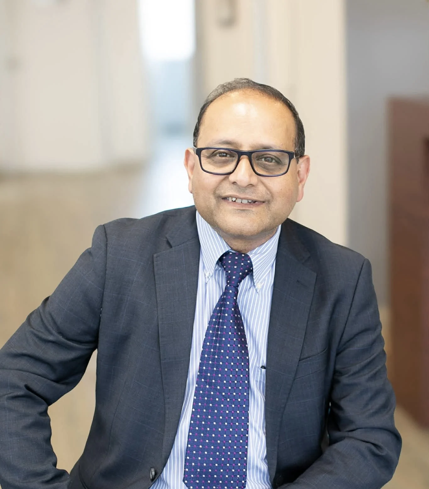 Dr Ravi Kumar Cherukuri in a navy suit and blue tie